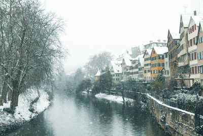 Buildings by river against clear sky