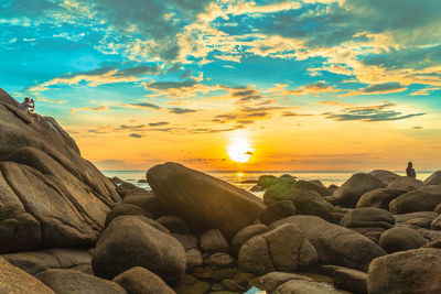 Rocks on shore against sky during sunset