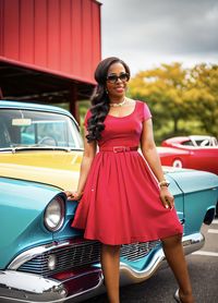 Portrait of young woman standing against car