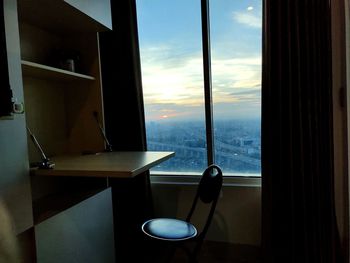 Table by sea against sky seen through home window