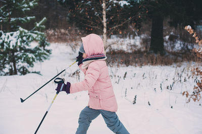 Rear view of woman with umbrella against trees during winter