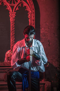 Man in costume holding sword at abandoned building during night