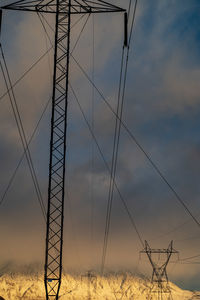 Low angle view of electricity pylon on field against sky