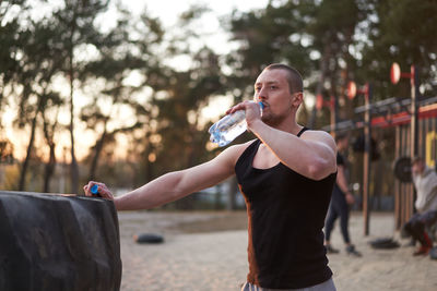 Man drinking water standing outdoors