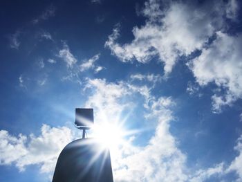Low angle view of sun shining through clouds