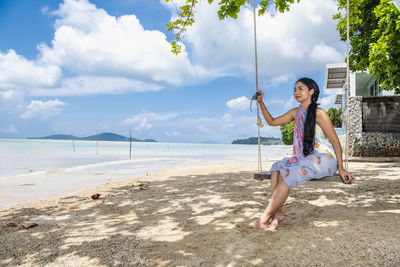 Beautiful woman sitting on a swing at the beach in phuket