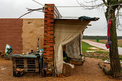 Old house on field by building against sky