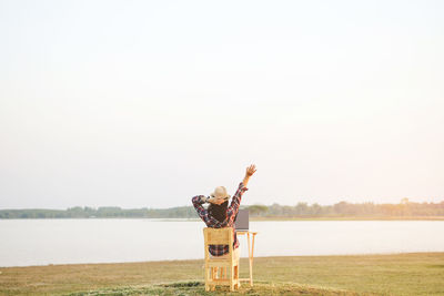 Man standing in front of lake against clear sky