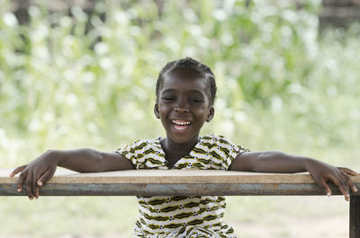 Cheerful girl looking away by table against plants