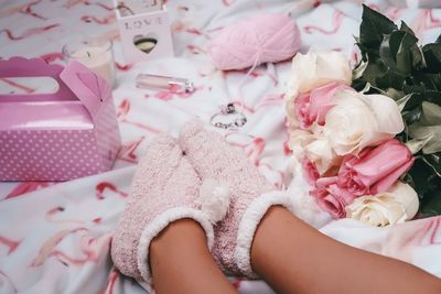 Low section of girl wearing socks by flowers and gift box on bed