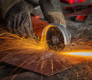 Close-up of man cutting metal at factory