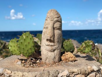 Close-up of stone sculpture by cactus against sky