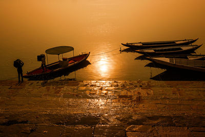 High angle view of men by boats moored on lake during sunset