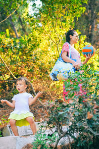 Full length of happy girl with flowers on tree