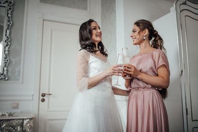 Bridesmaid and bride holding champagne flute