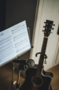 Close-up of microphone with musical note and guitar in background