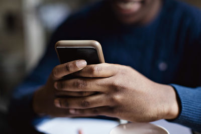 Social media addicted teenage boy using smart phone while studying at home