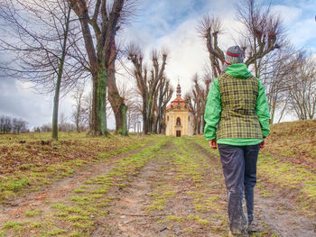 Rear view of man standing by bare trees