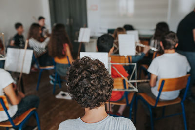 Rear view of people sitting in music classroom