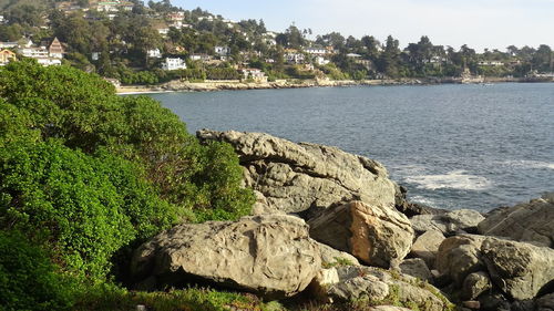 Scenic view of rocks by sea against sky