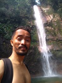 Portrait of young man against waterfall