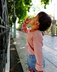 Side view of girl standing on footpath