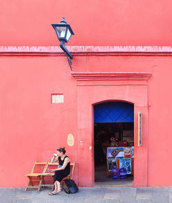 Woman sitting on chair against building