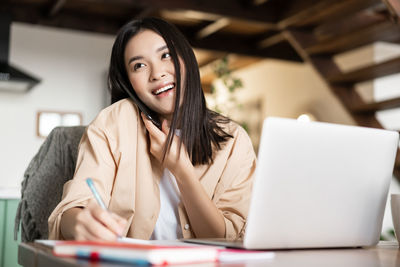 Portrait of young woman using laptop at home