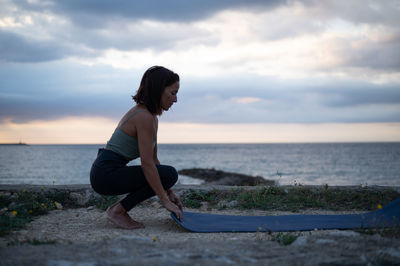 Rear view of woman standing at beach against sky