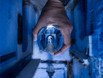 Cropped hand of person holding crystal ball in alley