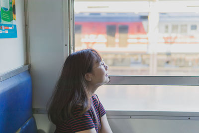 Side view of woman looking away through train window