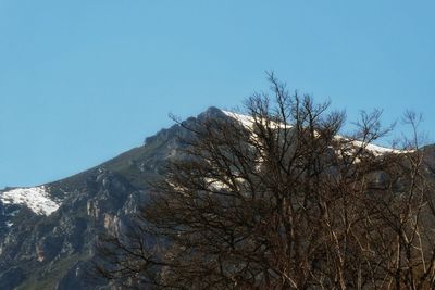 Low angle view of snowcapped mountain against clear blue sky