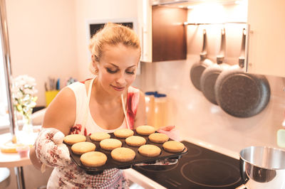 Woman with baking tray standing in kitchen