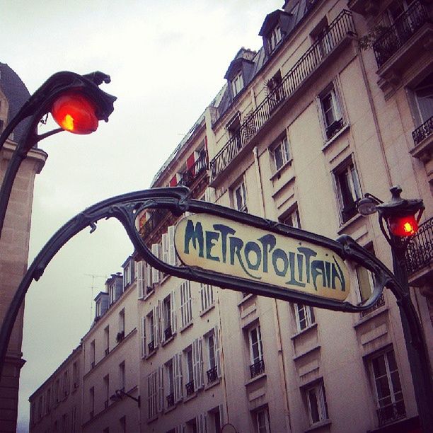 architecture, building exterior, built structure, low angle view, text, city, street light, building, sky, window, western script, lighting equipment, communication, road sign, residential building, outdoors, no people, lantern, residential structure, non-western script