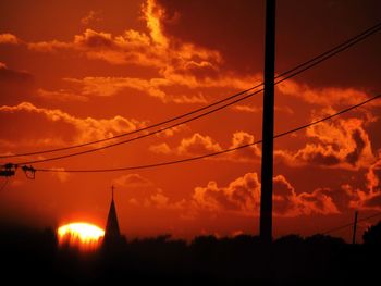 Silhouette trees against orange sky