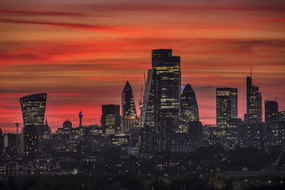 Modern buildings in city against sky during sunset