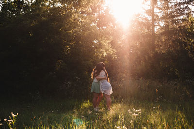 Lesbian couple embracing in forest during summer