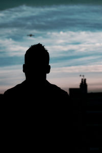 Rear view of silhouette man standing against sky