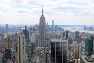 Aerial view of buildings in city against cloudy sky