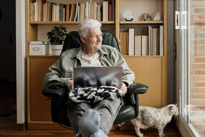 Full length portrait of man sitting at home