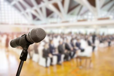 Close-up of microphone by people sitting in auditorium