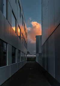 Footpath amidst buildings against sky during sunset