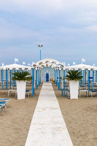 Empty chairs on beach against sky