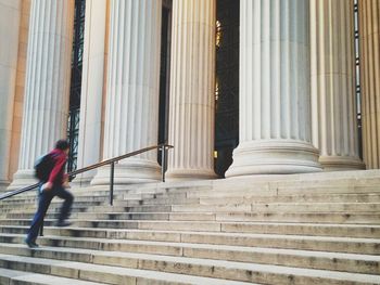 Side view of blurred man walking up building front stairs