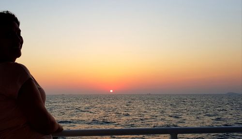 Man looking at sea against sky during sunset