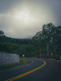 Road by trees against sky