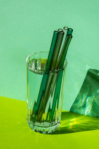 Reusable glass straws in glass with water on green background eco-friendly drinking straw set with