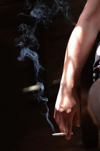 Cropped image of man holding burning cigarette