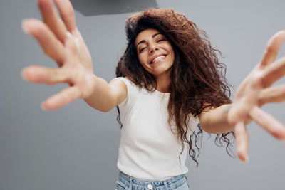 Young woman with arms raised standing against wall