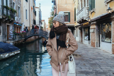 Young woman standing by canal in city